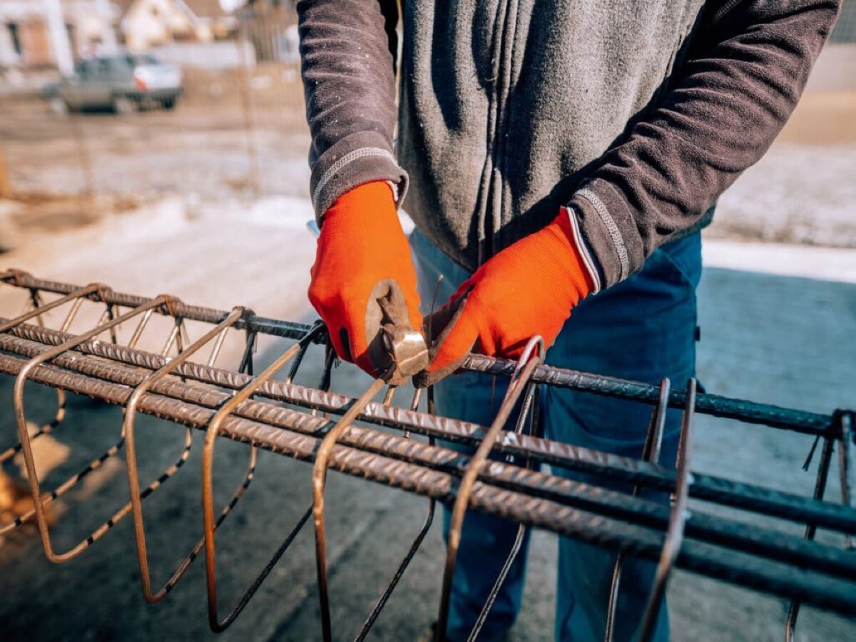 TREMO worker adjusting rebar with precision, equipped with proper safety gear